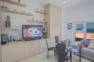 a living room with a television and a table with chairs at Pallini Court in Protaras