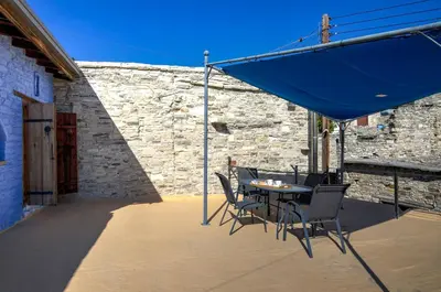 a patio with a table and chairs and a blue umbrella at Blue Oak House in Kato Drys