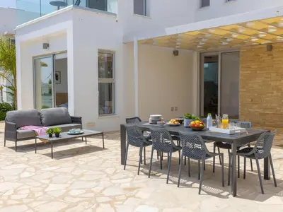 a patio with a table and chairs and a couch at Milos lifestyle villas H27 in Protaras
