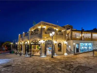 a large brick building with lights on it at night at Nissi 3 Pool Access Garden Apartment in Ayia Napa