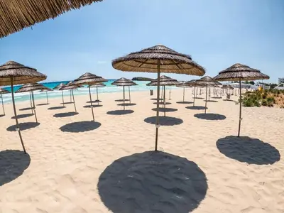a group of umbrellas on a beach with the ocean at Nissi Golden Sands Family Apartment in Ayia Napa