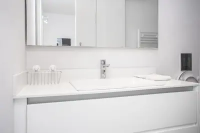 a white bathroom with a sink and a mirror at Mayra Seafront Luxury Apartment (BREAKBOOKING-CY) in Limassol