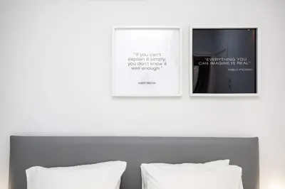 two framed pictures above a bed with white pillows at Mayra Seafront Luxury Apartment (BREAKBOOKING-CY) in Limassol