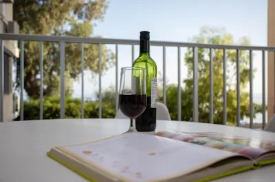 a glass of wine sitting on a table with a book at Mayra Seafront Luxury Apartment (BREAKBOOKING-CY) in Limassol