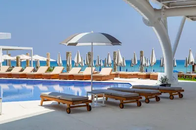a swimming pool with lounge chairs and an umbrella at Flamingo Paradise Beach Hotel - Adults Only in Protaras