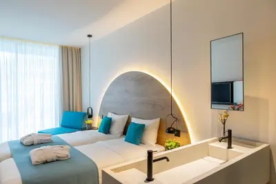 a hotel room with two beds and a mirror at Flamingo Paradise Beach Hotel - Adults Only in Protaras