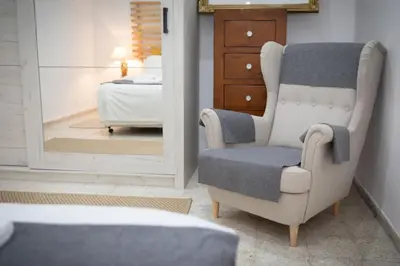 a bedroom with a chair and a bed and a mirror at LIMASSOL AKROTIRI BEACH VINE COTTAGE a in Limassol