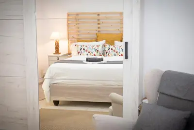 a bedroom with a white bed and a chair at LIMASSOL AKROTIRI BEACH VINE COTTAGE a in Limassol