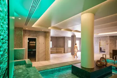 a woman walks through a hotel lobby with a swimming pool at ROBINSON Cyprus in Alaminos