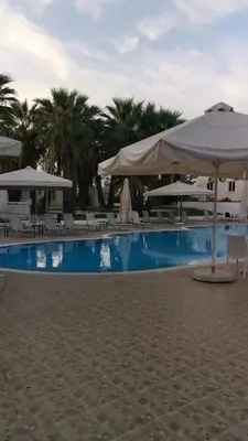 a swimming pool with umbrellas and chairs on a beach at Garden Luxury Apartment Ayia Napa in Ayia Napa