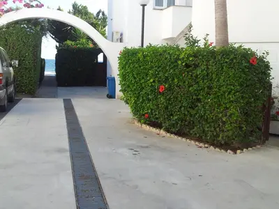 a bush with red flowers next to a sidewalk at Yialos Holiday Apartments in Pervolia