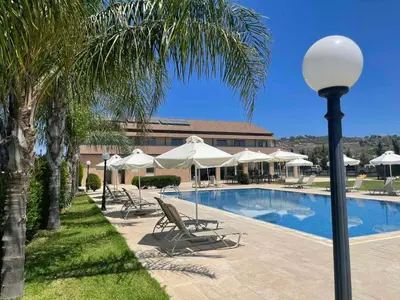 a pool with chairs and umbrellas next to a building at Protaras Tennis and Country Club in Protaras