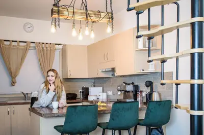 a woman sitting at a counter in a kitchen at Aprosmeno Jacuzzi House 2 in Agros