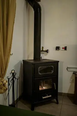a black stove in a room with a fireplace at Aprosmeno Jacuzzi House 2 in Agros