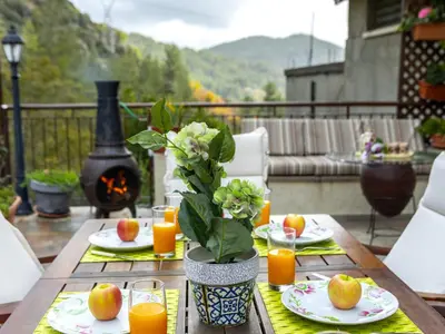 a wooden table with plates of food and orange juice at Troodos Riverside Cottage in Kato Amiandos