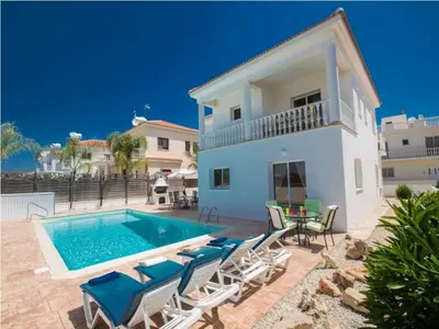 a villa with a swimming pool and chairs and a house at Carilisto Villas Big 4 Bedrooms in Center of Ayia Napa in Ayia Napa