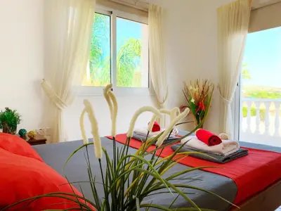 a bedroom with a bed with red sheets and a window at Carilisto Villas Big 4 Bedrooms in Center of Ayia Napa in Ayia Napa