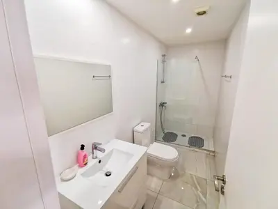 a white bathroom with a sink and a shower at Vasilo Court Seaview City Apartment in Larnaka