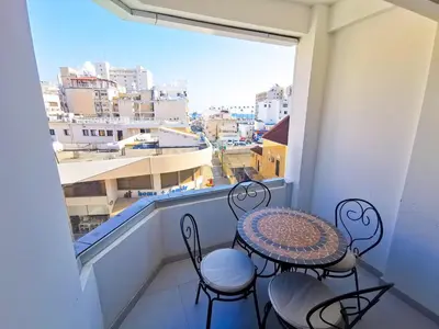 a balcony with a table and chairs and a large window at Vasilo Court Seaview City Apartment in Larnaka