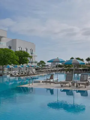 a swimming pool with chairs and umbrellas in a resort at Atlantica Aqua Blue in Protaras