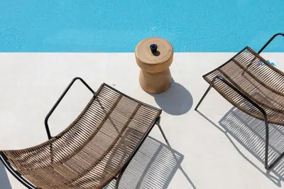 two chairs and a vase sitting next to a pool at Atlantica Aqua Blue in Protaras