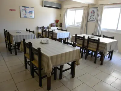 a dining room with tables and chairs and windows at Denis Hotel in Nicosia