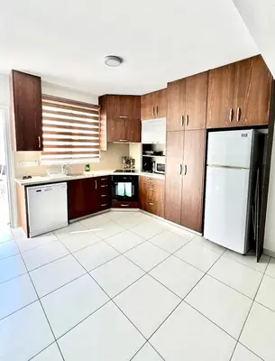 a kitchen with wooden cabinets and a white tile floor at Dafni Villa Ekaterina 3 bdrm in Protaras