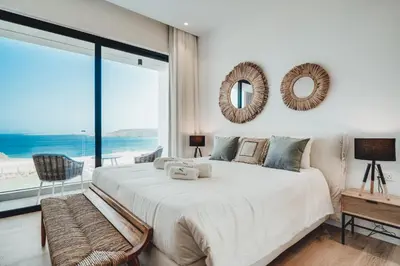 a bedroom with a large bed with a view of the ocean at Periyiali Konnos Villas Beach Resort in Protaras