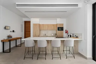 a kitchen with white counters and white counter stools at Periyiali Konnos Villas Beach Resort in Protaras