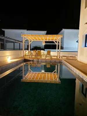 a swimming pool with chairs and a deck at night at St Nicolaos Villa Ekaterina 3 bdrm in Protaras