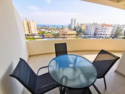 a glass table and chairs on a balcony with a view at License to Chill Apartment in Larnaka