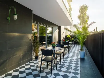 a restaurant patio with tables and chairs on a checkered floor at LIV URBAN Suites in Larnaka