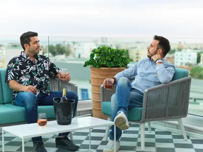 two men sitting in chairs on a balcony with drinks at LIV URBAN Suites in Larnaka