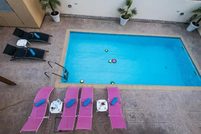 an overhead view of a swimming pool with pink chairs at Luxury Villa Regina in Protaras