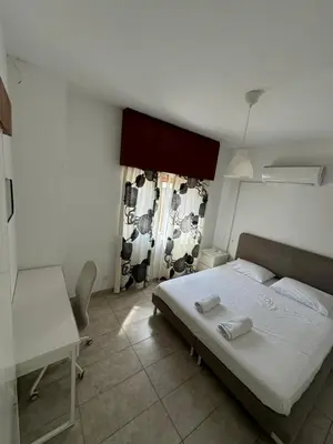 a bedroom with a bed and a desk and a window at Milky in Limassol