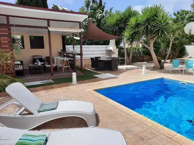 a swimming pool with two lounge chairs and a house at Villa Anastassia in Ayia Napa