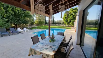a patio with a table and chairs and a pool at The Stone Villa in Pissouri