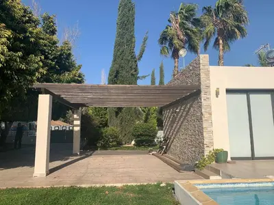 a wooden pavilion with a swimming pool and palm trees at The Stone Villa in Pissouri