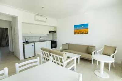 a living room with a couch and a table and chairs at Liquid Hotel Apartments in Ayia Napa