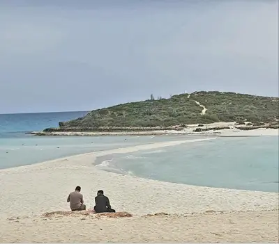 two men sitting on a sandy beach near the ocean at Panthoma Casa in Ayia Napa