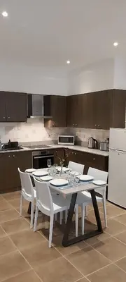 a kitchen with a table with white chairs and a white refrigerator at Panthoma Casa in Ayia Napa
