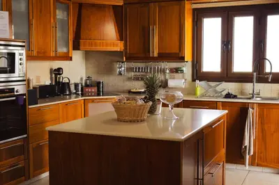 a kitchen with wooden cabinets and a island with a wine glass at Kasparis View Residence in Pano Lefkara