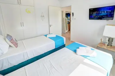 a living room with two beds and a tv at SunnyVillas: 4BR Villa☆Private Pool + Jacuzzi - Villa Amelie in Protaras