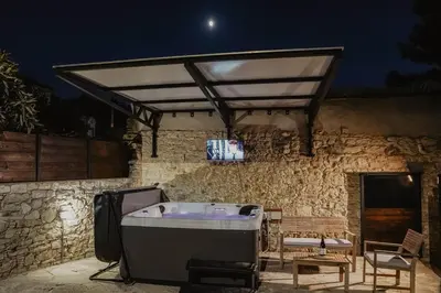 a bath tub and a tv on a stone wall at The Stonehouse Suites with Private Bath Spas in Limassol
