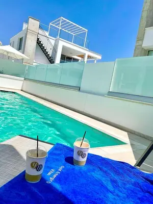 two cups on a blue towel next to a swimming pool at Imperial Jade Villas Gold Emerging Villas 1 in Protaras