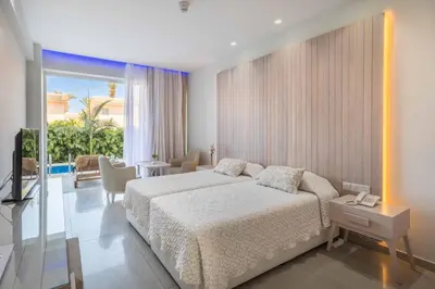 a bedroom with a bed and a living room at Tasia Maris Beach Hotel - Adults Only in Ayia Napa