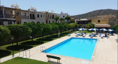 a swimming pool with chairs and umbrellas next to a building at skeleas 10 in Pissouri