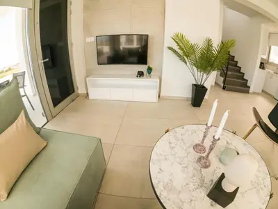 a living room with a table and a tv at Imperial Jade Villas Gold Emerging Villas 3 in Protaras