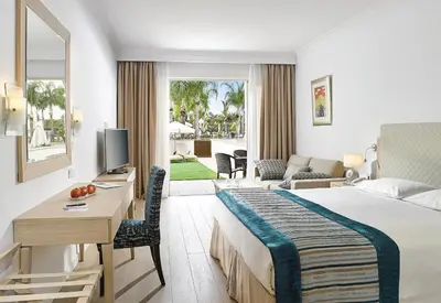 a hotel room with a bed and a desk with a television at Olympic Lagoon Resort Ayia Napa in Ayia Napa
