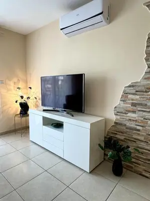 a living room with a television on a white cabinet at NISSI BEACH Apt 7 BIG VERANDA AND FREE WIFI in Ayia Napa